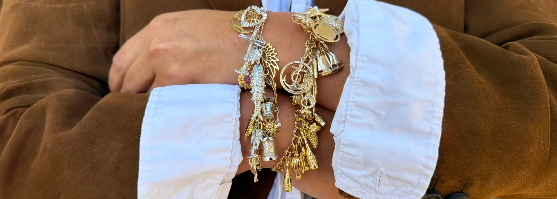 Gold charm bracelets stacked on a wrist