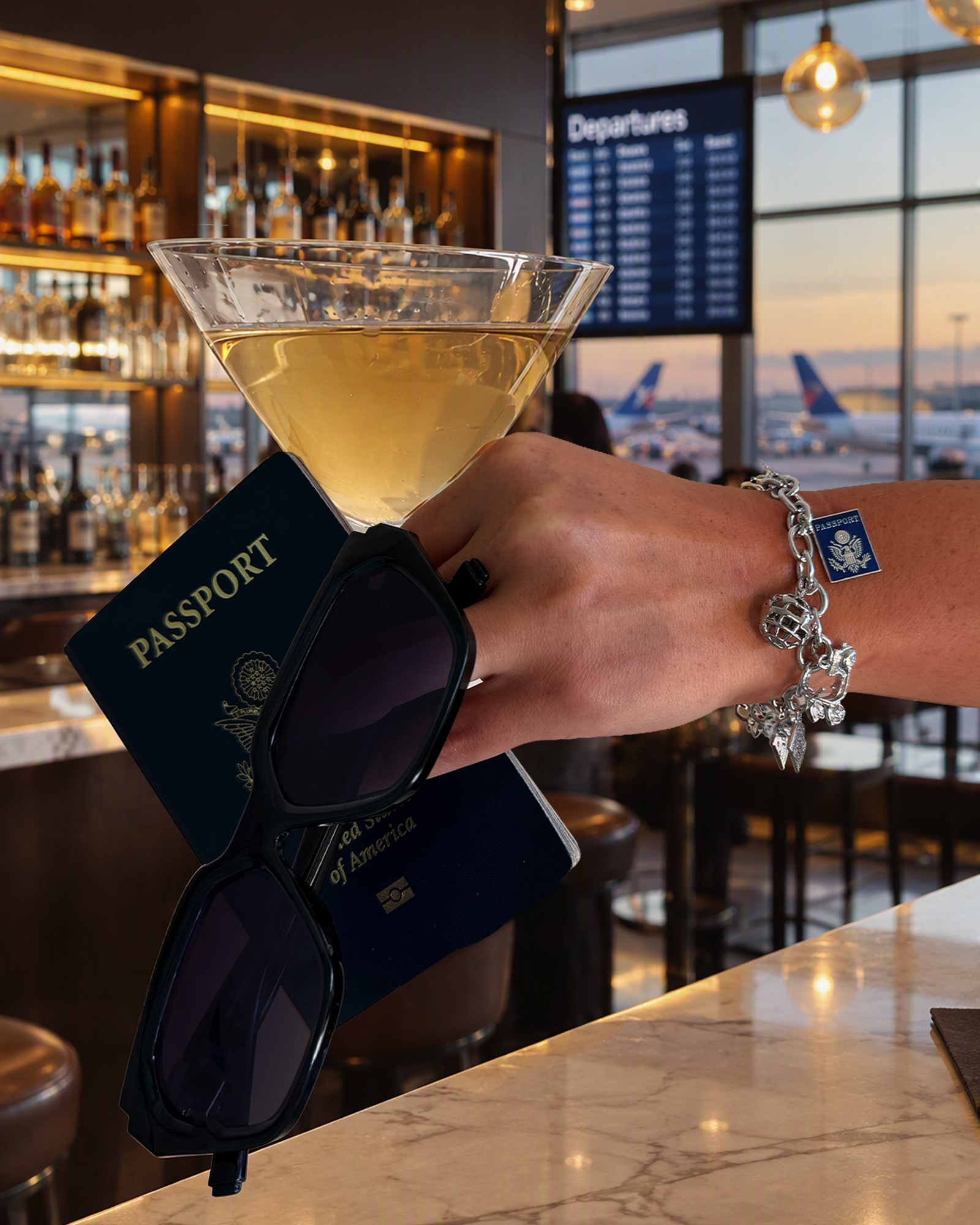 A raised glass of white wine at an airport bar, holding a United States passport and sunglasses, with a silver charm bracelet on the wrist and departures board and planes behind